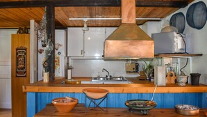 A kitchen with a wooden ceiling, a copper range hood, a sink, and a blue countertop.