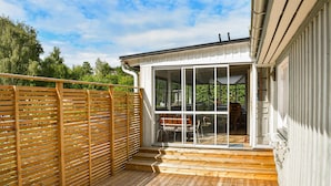 A wooden deck with a glass door leading to an outdoor seating area.