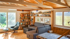 A cozy living room with a large bookshelf, a comfortable sofa, and a dining table.
