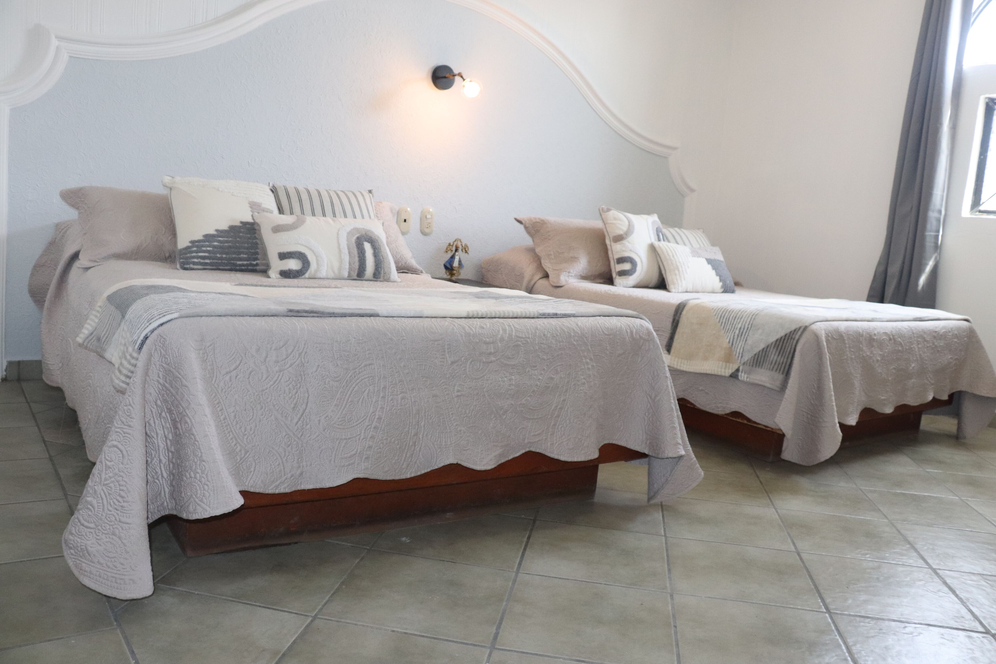 Un dormitorio con dos camas, cada una con cubrecolcha blanco y varias almohadas.