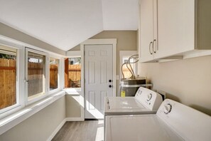 A laundry room with a washer and dryer, a water heater, and a door leading to a backyard.