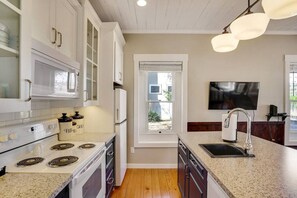 A kitchen with white cabinets, a stainless steel range, a microwave, and a sink with a faucet.