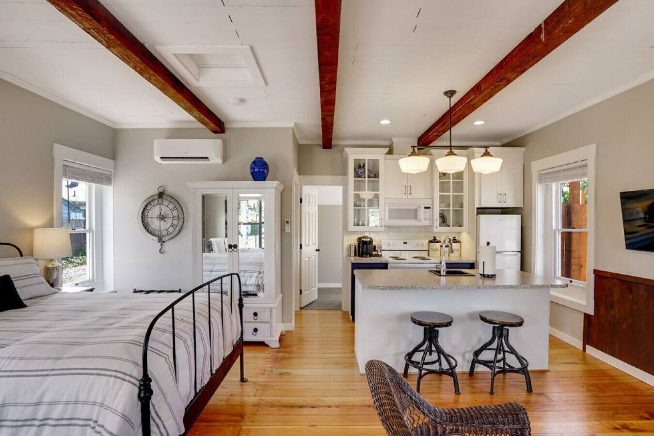 Une chambre spacieuse avec un grand lit, une armoire et une horloge au mur.