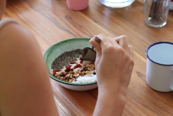 A person preparing a meal with a bowl of ingredients and a mug on a wooden table.