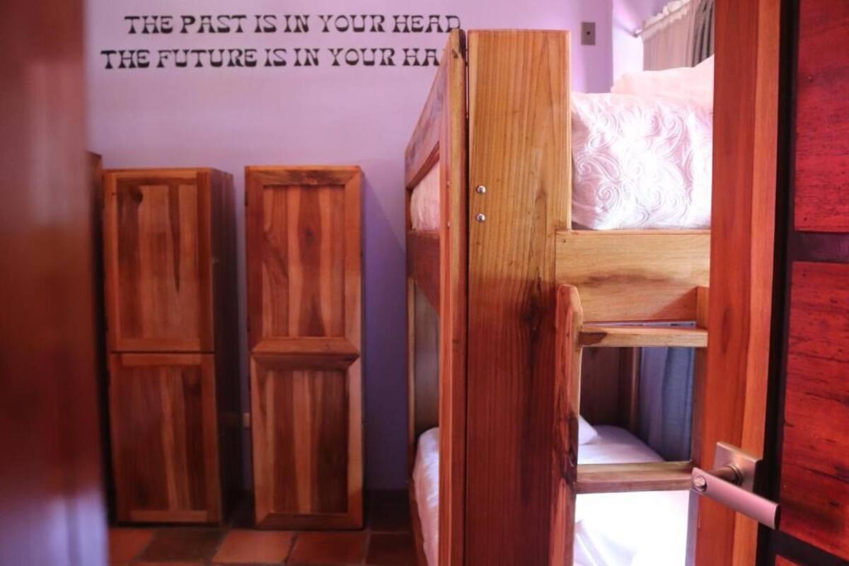 A bunk bed room with wooden furniture and a motivational quote on the wall.