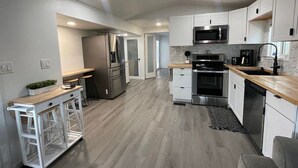 Una cucina moderna con mobili bianchi, elettrodomestici in acciaio inossidabile e un piano di lavoro in legno.