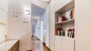 Ein Flur mit Holzboden, weißen Wänden und einem Bücherregal voller Bücher.