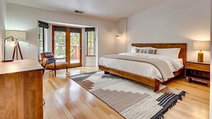 A bedroom with a wooden bed, a desk, a chair, and a large window with a view of the outdoors. - Private Ski, Lake & Golf Chalet! Walk to Lake (Tahoe Vista)