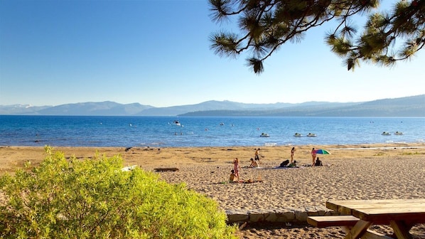 A beach with people, boats, and mountains in the background.