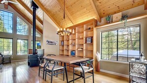 A spacious room with a wooden ceiling, large windows, a dining table with chairs, and a built-in bookshelf. - Private Ski, Lake & Golf Chalet! Walk to Lake (Tahoe Vista)