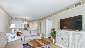 A living room with a sofa, a coffee table, a TV, and a cabinet. - Beachfront Bliss! Oceanfront Pool! Great Location!  Ocean Trillium 702 (New Smyrna Beach)
