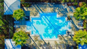 An aerial view of a swimming pool with surrounding palm trees and a covered seating area. - 30A Treetop Retreat • Shared Pool + Private Beach Access + Bikes | Pura Vida (Seacrest Beach)