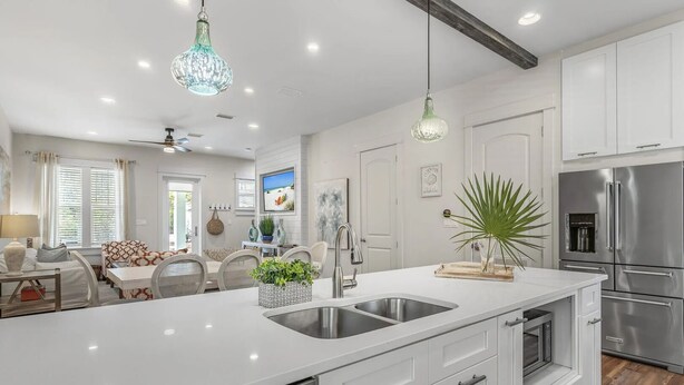 A modern kitchen with white cabinetry, stainless steel appliances, and a central island with a sink. - 30A Treetop Retreat • Shared Pool + Private Beach Access + Bikes | Pura Vida (Seacrest Beach)