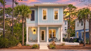 A two-story house with a porch, a covered patio, and a view of the surrounding trees. - 30A Treetop Retreat • Shared Pool + Private Beach Access + Bikes | Pura Vida (Seacrest Beach)