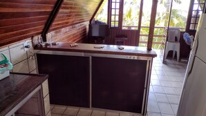 A kitchen with a wooden counter, tiled floor, and a view of palm trees outside. - Beautiful chalet with panoramic views (Ubatuba)