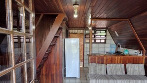 A compact kitchen with a refrigerator, a wooden counter, and a striped sofa. - Beautiful chalet with panoramic views (Ubatuba)