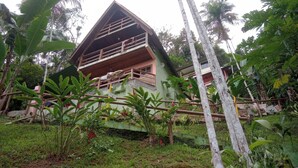 A two-story house with a balcony, surrounded by lush greenery and banana trees. - Beautiful chalet with panoramic views (Ubatuba)