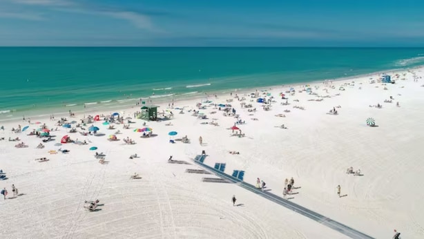 A wide beach with numerous umbrellas and people.