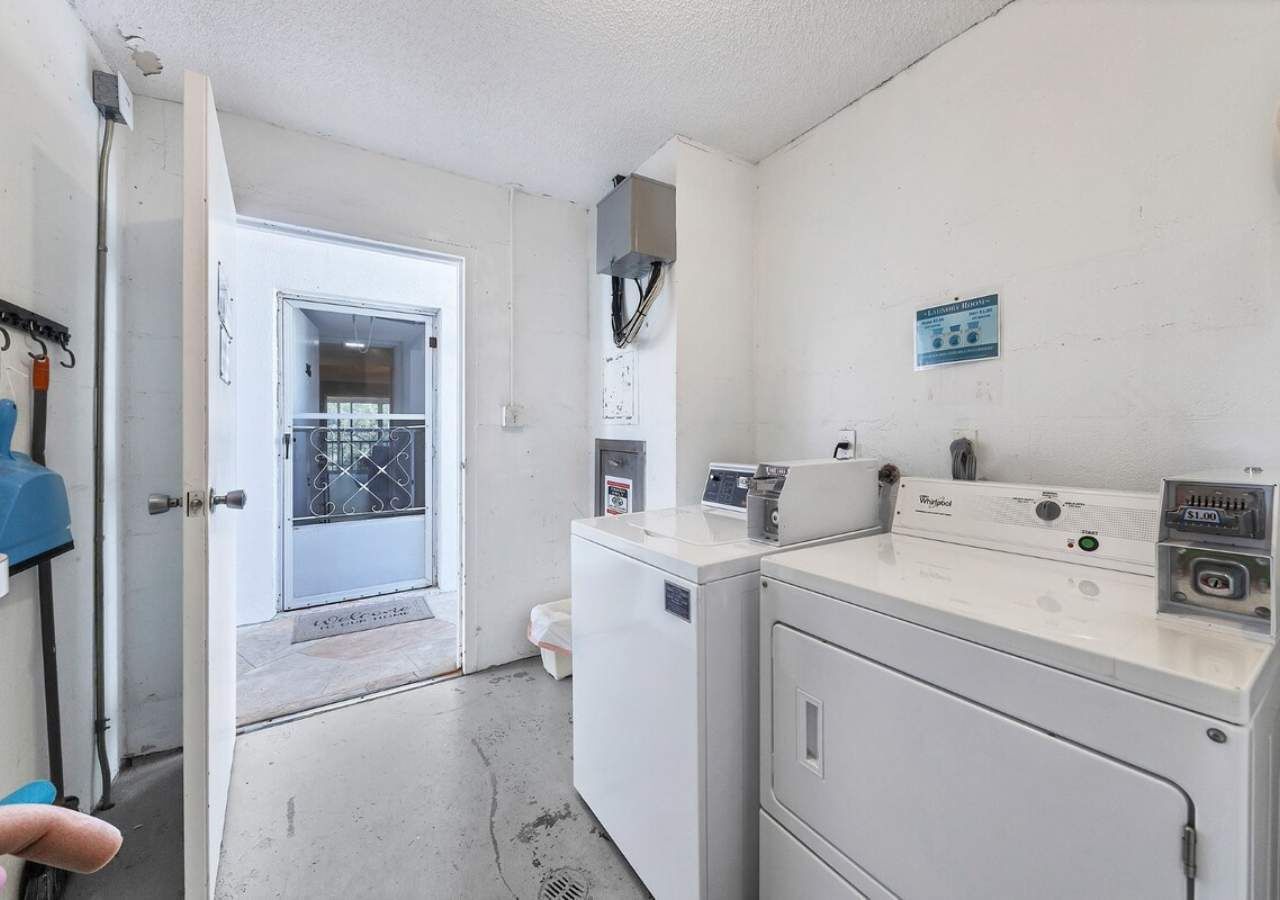 A laundry room with a washing machine, dryer, and a door leading to another room.