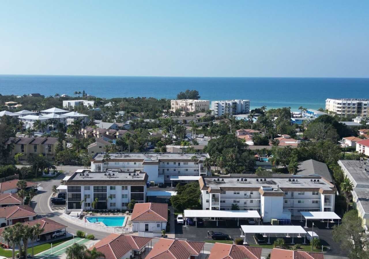 A coastal hotel with multiple buildings, a swimming pool, and a view of the ocean.
