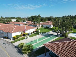 Zona residencial con casas, un espacio verde con parque infantil y cielo despejado.