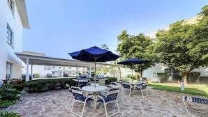 A patio area with outdoor seating, a barbecue grill, and umbrellas.