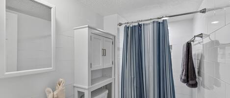 A bathroom with a white sink, a toilet, a shower curtain, and a towel rack.
