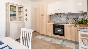A kitchen with white cabinets, a black oven, and a tiled backsplash. - VILLINO LORENZO for Rent 3 min from Porto Cesareo with Pool (Boncore)