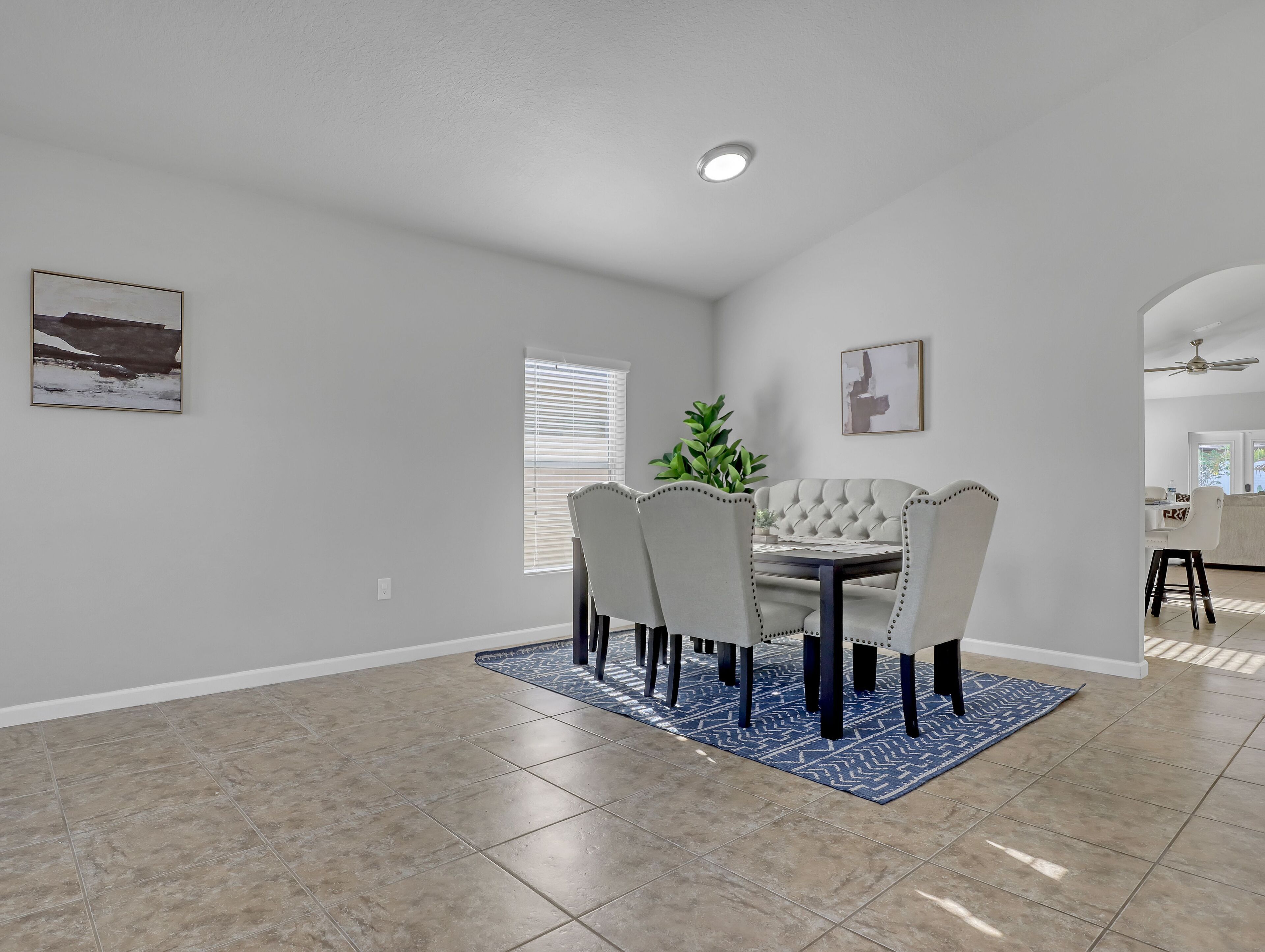 A dining area with a table and chairs, a potted plant, and artwork on the walls.