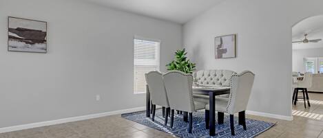 A dining area with a table and chairs, a potted plant, and artwork on the walls.