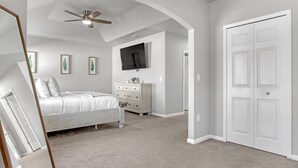 A bedroom with a bed, dresser, TV, and arched ceiling. - Melbourne Beach House (West Melbourne)