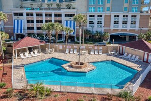 Ein Hotelpoolbereich mit mehreren Pools, Liegestühlen und Palmen.