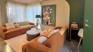 Een woonkamer met twee banken, een salontafel, een lamp en een schilderij aan de muur.