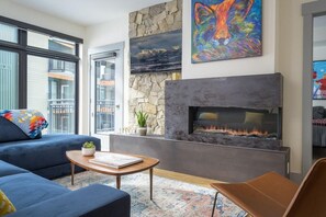 A modern living room with a fireplace, a sofa, a coffee table, and a painting on the wall.