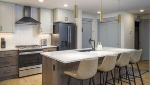 A modern kitchen with a central island, stainless steel appliances, and pendant lighting.