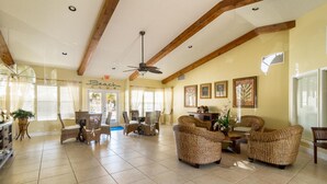 A spacious lounge area with wicker furniture, a ceiling fan, and framed artwork on the walls. - Precious Condo, 3 Blocks to Beach.. Happy Place! (Indialantic)