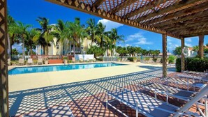 A pool area with a wooden pergola, lounge chairs, and palm trees. - Precious Condo, 3 Blocks to Beach.. Happy Place! (Indialantic)