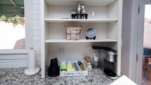 Eine Küche mit einer Kaffeebar und Teeausstattung, einem Wasserkocher, einer Kaffeemaschine und einem Mixer auf der Arbeitsfläche.