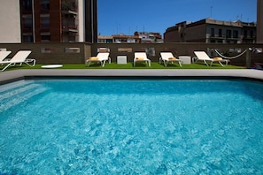 Ein Swimmingpool mit klarem, blauem Wasser, umgeben von weißen Liegestühlen.