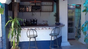 A bar area with a counter, two stools, and a shelf with bottles. - Island Inn Boracay (Boracay Island)