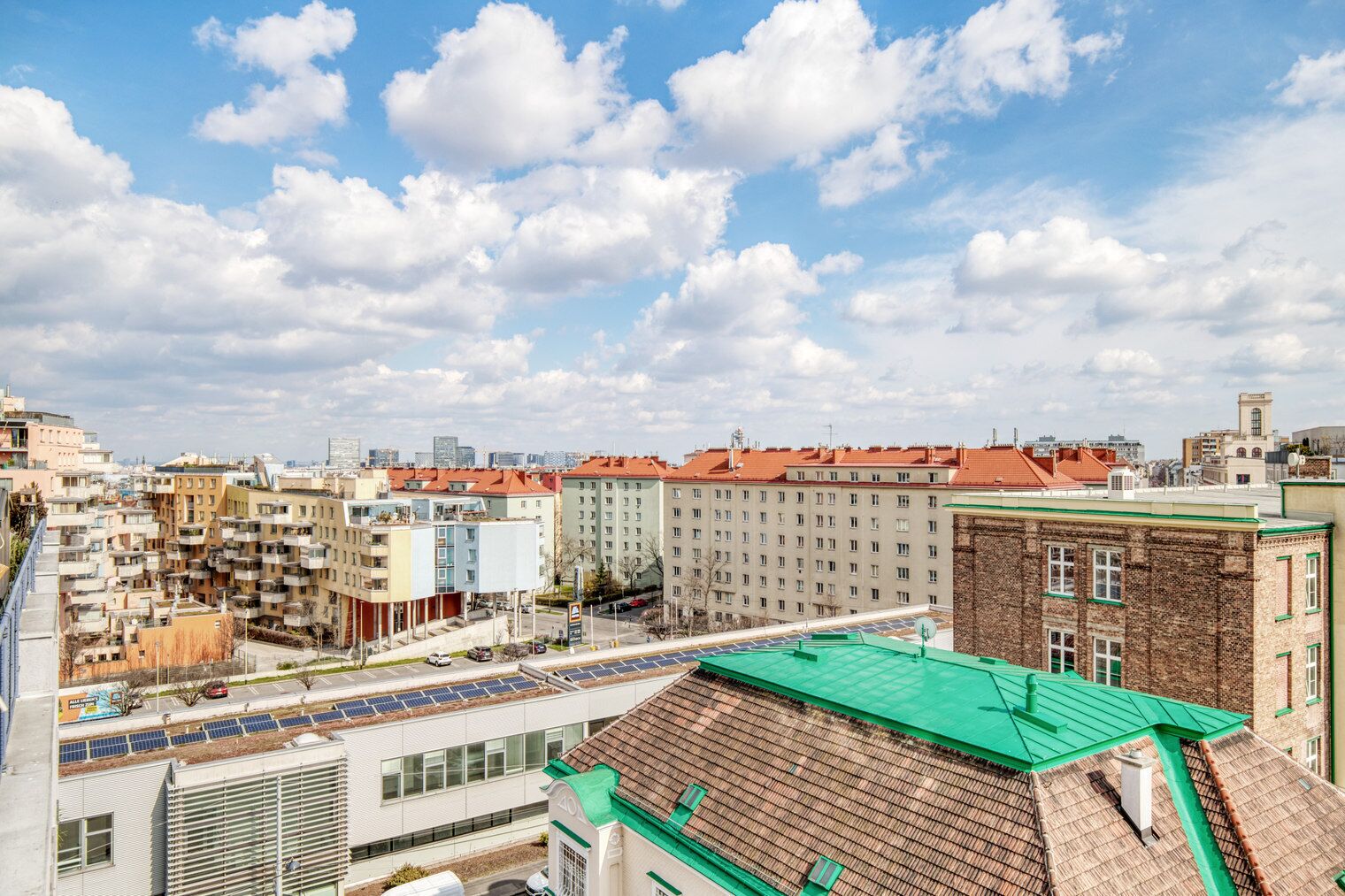 Un paysage urbain mêlant bâtiments modernes et traditionnels, un ciel dégagé et un parking équipé de panneaux solaires.