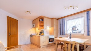Eine kleine Küche mit Holzschränken, einem Esstisch und einem eingebauten Ofen.