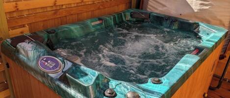A hot tub with a control panel, set against a wooden wall.
