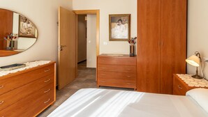 A bedroom with a bed, wooden dresser, wardrobe, and a mirror. - Port de Llançà 34 - Apartment with sea views (Llança)