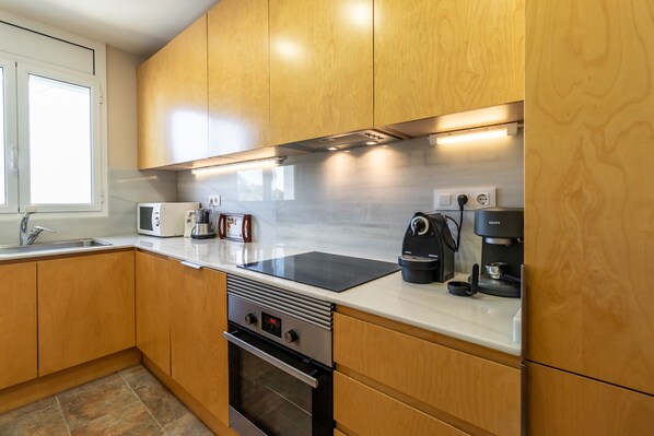 Una cocina moderna con armarios de madera, estufa de acero inoxidable, cafetera y tostadora.