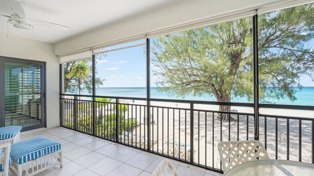 Un balcon avec vue sur la plage, un sol carrelé de couleur blanche et du mobilier d’extérieur.
