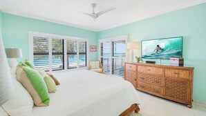 Une chambre à coucher comprenant un lit, une télévision, une commode et un ventilateur de plafond.