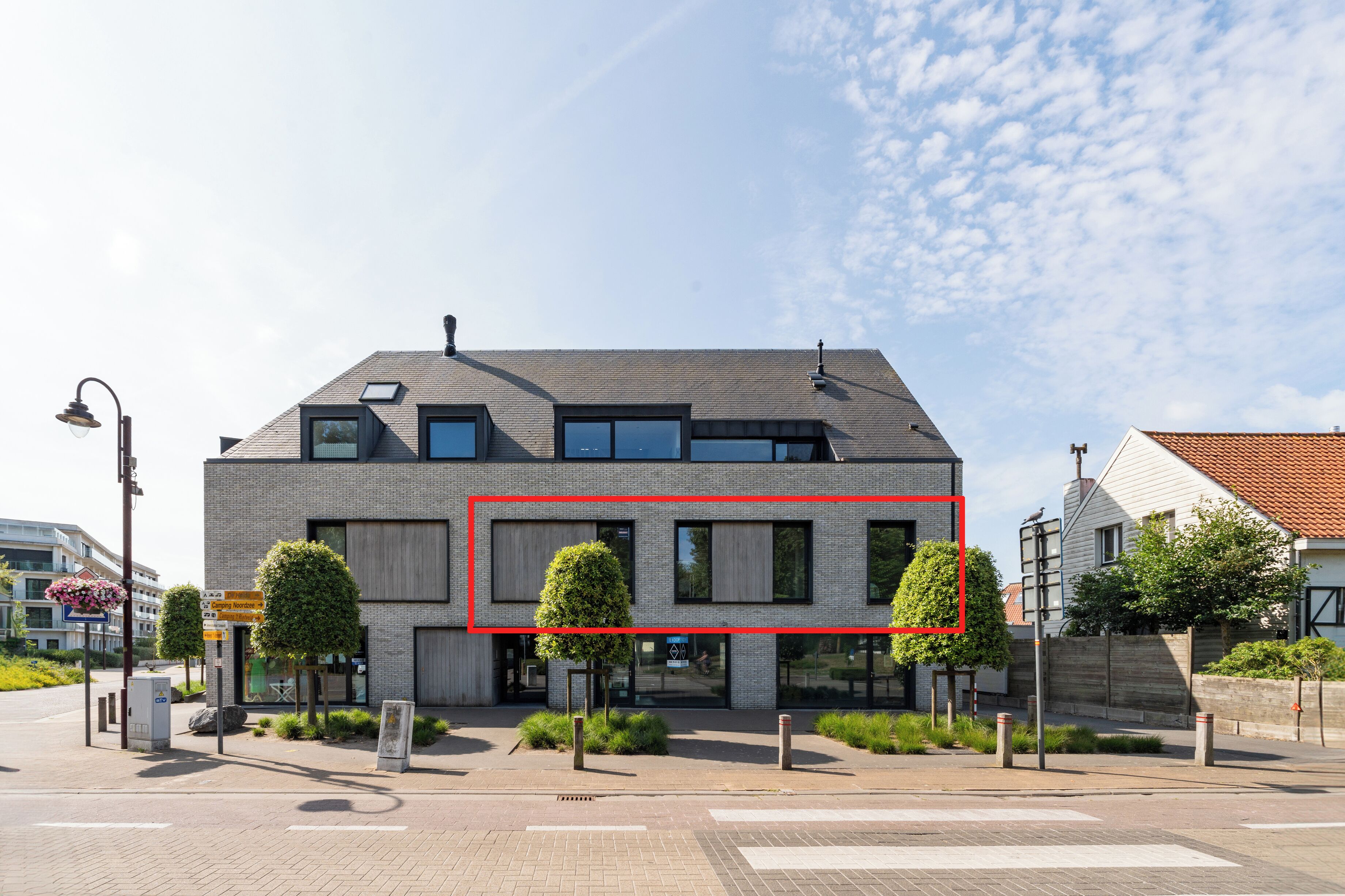 A modern building with a flat roof, large windows, and a brick facade.