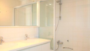 A bathroom with a white sink, a mirror, and a glass-enclosed shower. - Golf & Beach C2 - beautiful 3-bedroom apartment 50 m from the beach (De Haan)