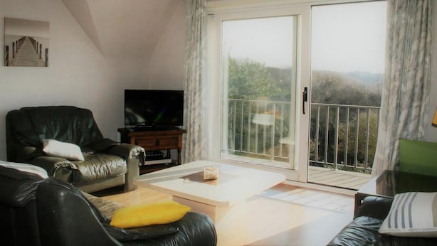 A living room with a TV, a sofa, a coffee table, and a sliding glass door to a balcony. - Golf & Beach C2 - beautiful 3-bedroom apartment 50 m from the beach (De Haan)
